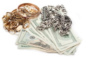 Gold and silver jewelry on a pile of cash